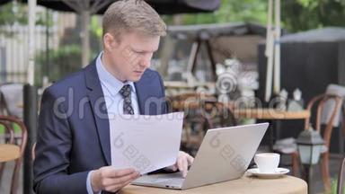 商务人士阅读<strong>合约</strong>及在户外咖啡厅使用手提电脑
